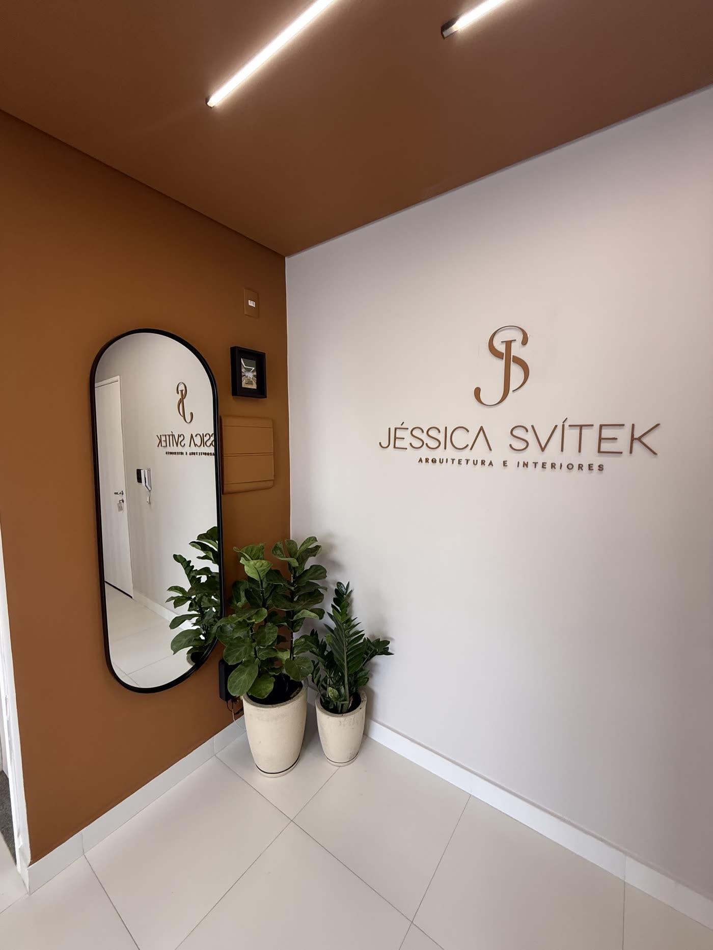 Entrada do escritório Jéssica Svítek, com parede terracota e logo em relevo