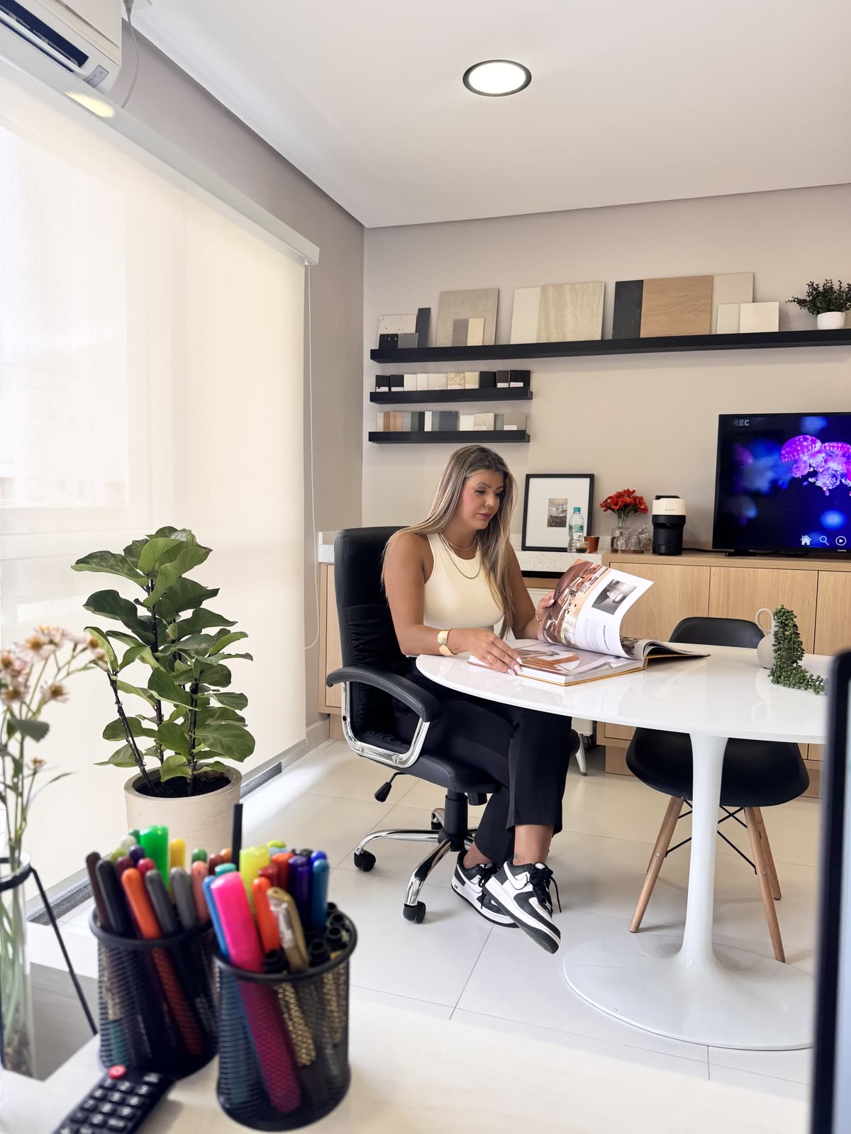 Jéssica trabalhando no escritório, folheando referências de materiais